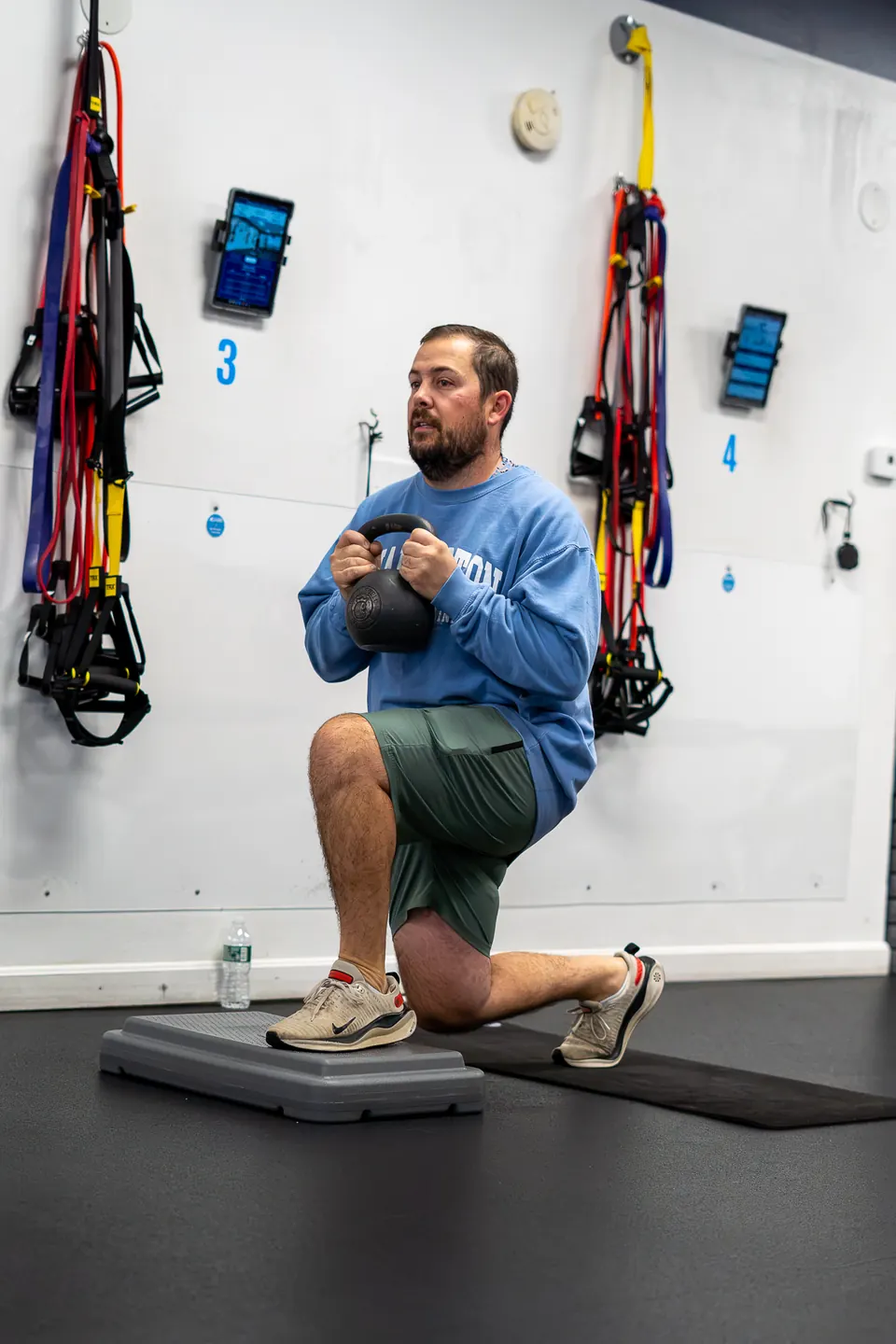 Member doing a kneeling dumbbell press