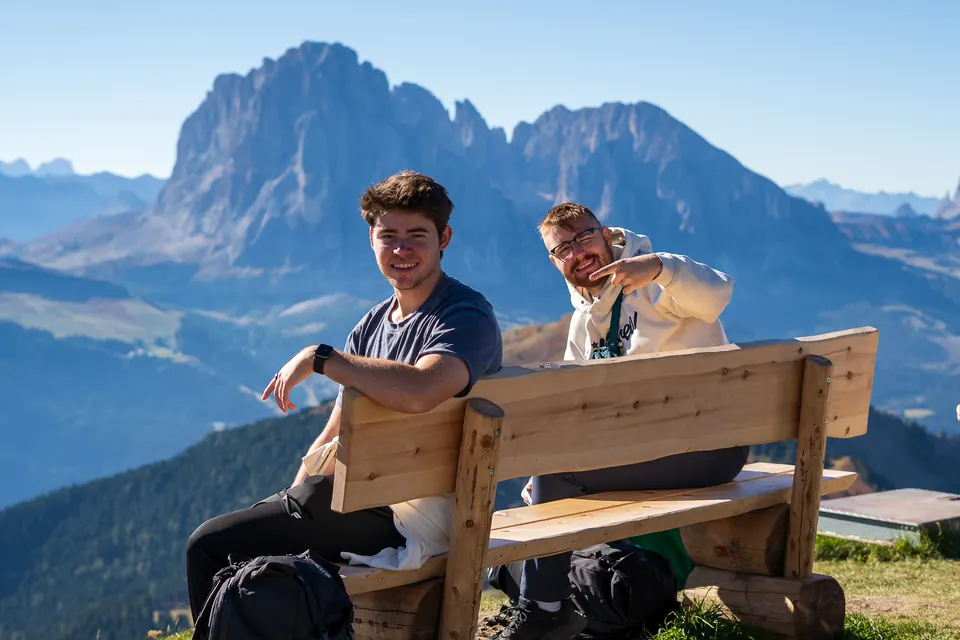 Two friends on a bench beneath the jagged peaks of the Dolomites