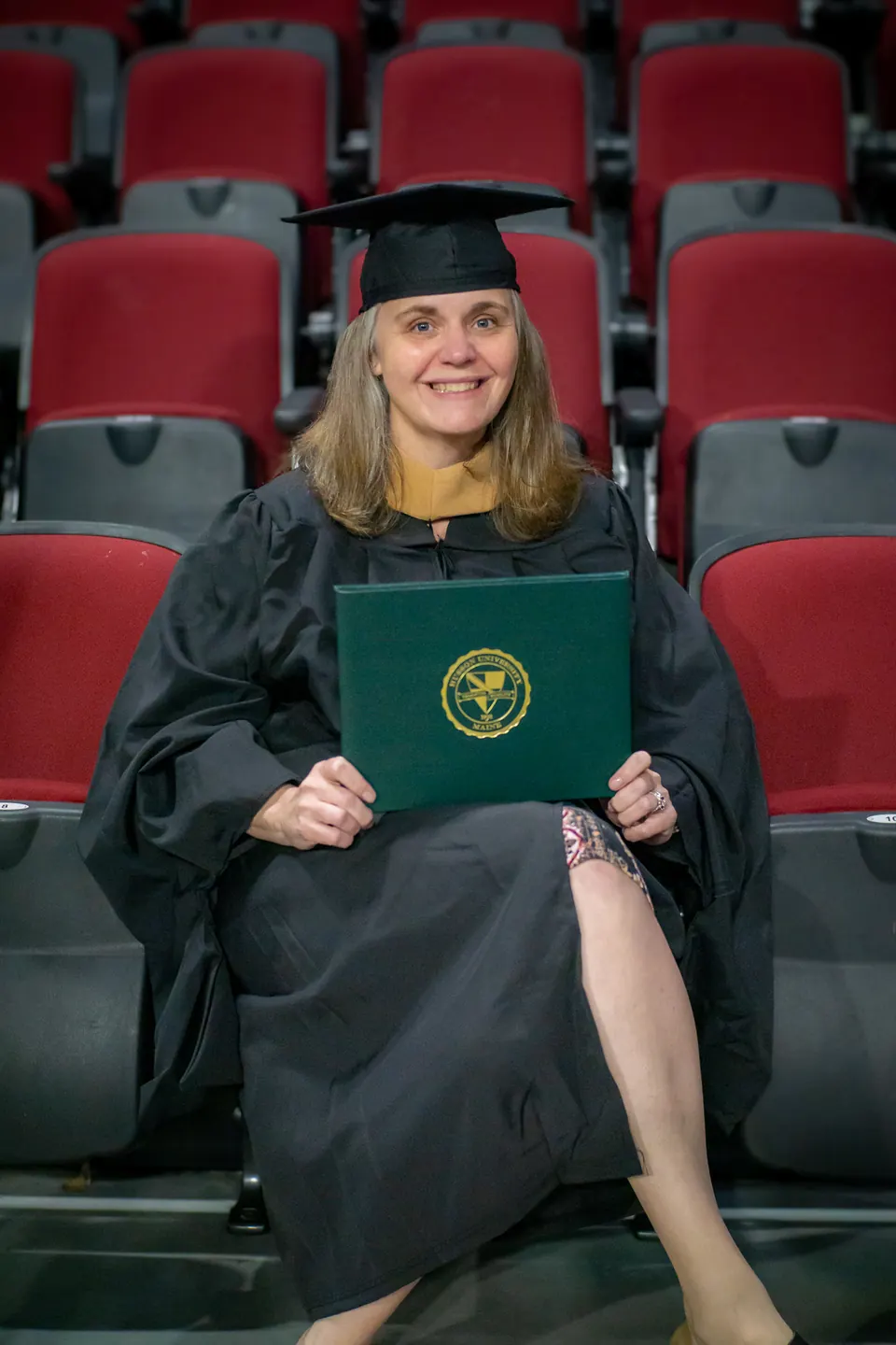 Graduate seated in an arena with her diploma