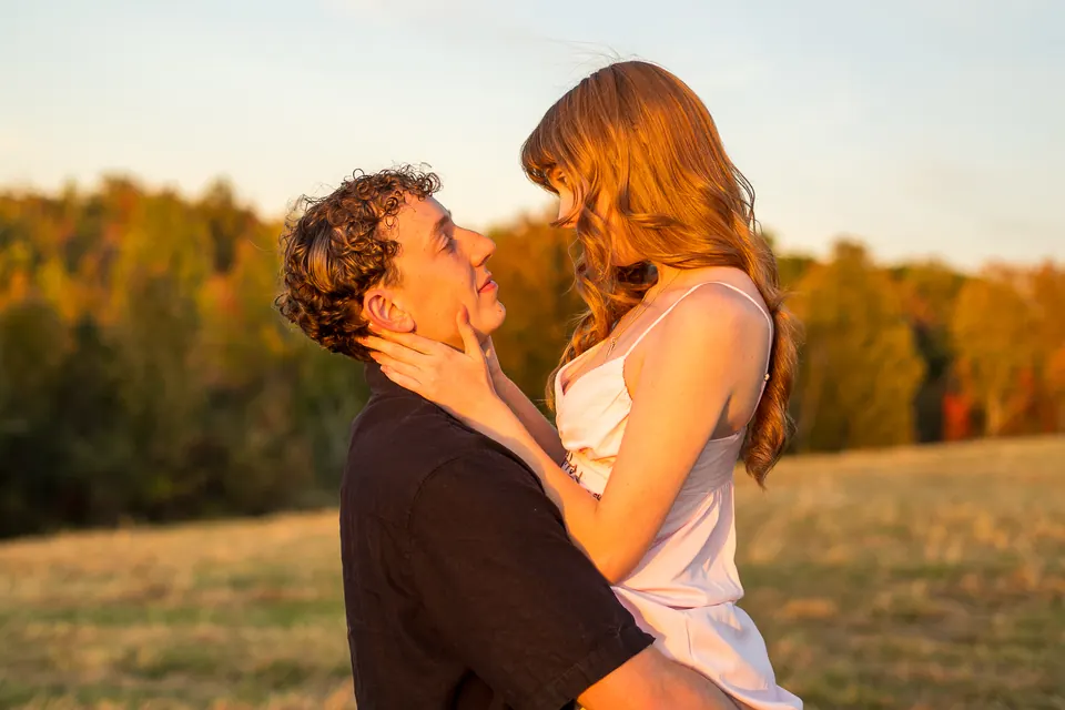 Couple embracing in a field with fall trees