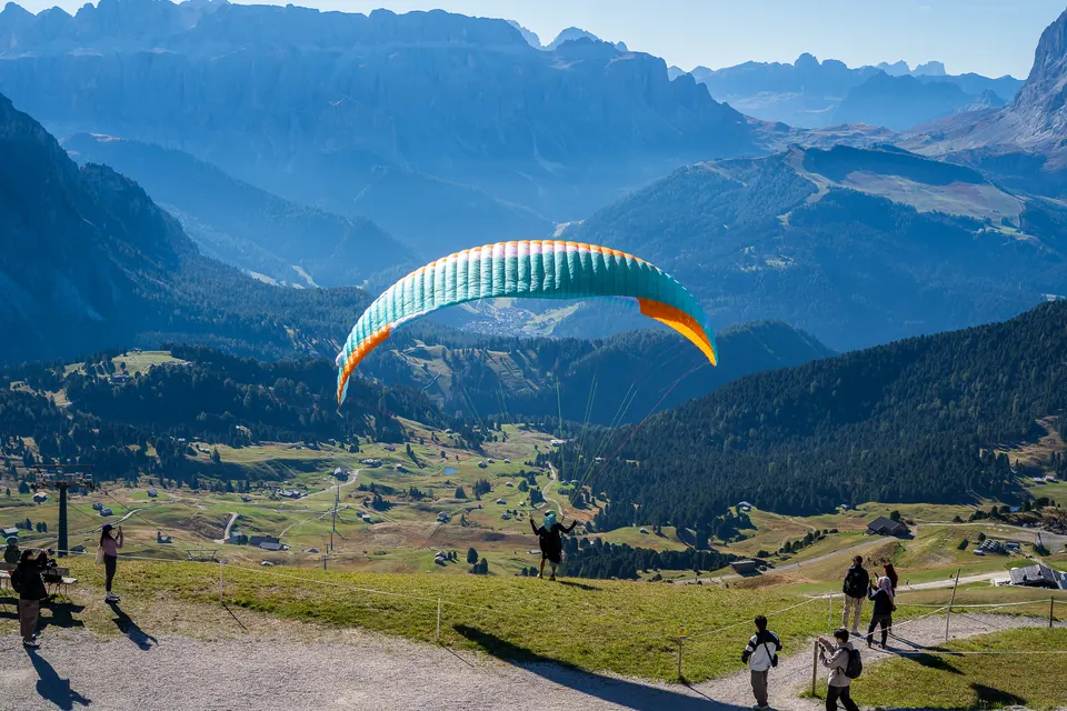 Paraglider over a green alpine valley
