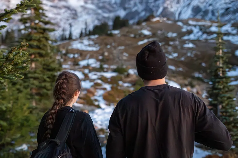 Two hikers looking out over a snowy alpine valley