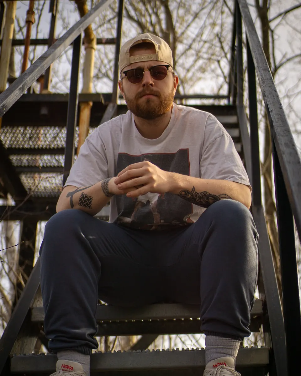 Man in sunglasses sitting on an outdoor metal staircase